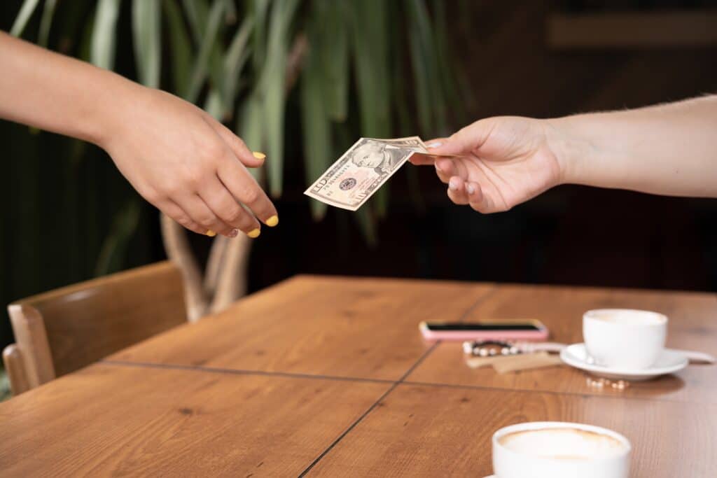 Woman Hand Holding US Dollar Banknotes Giving Cafe Waitress money